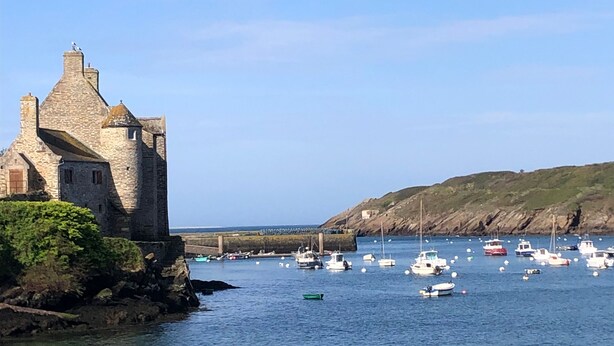 A stone building by a harbor with boats. - La Maison des Seigneurs les pieds dans l'eau (Le Conquet)