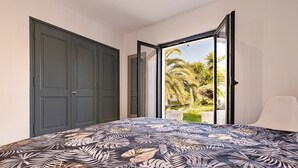 Une chambre à coucher avec un lit, une porte et une vue sur des palmiers.
