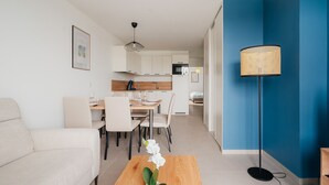Un salon moderne avec un canapé, une table à manger et des chaises, une cuisine en arrière-plan et un mur d’accent bleu.