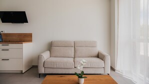 Un soggiorno minimalista con un divano beige, un tavolino in legno e una TV a parete.
