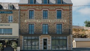 En byggnad med en fasad av sten, flera fönster och en skylt med texten ”GITES DES PIERRES SCONNANTES”.