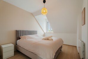 Um quarto com uma cama, mesa de cabeceira e janela.