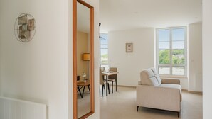 Ein modernes Wohnzimmer mit einem großen Spiegel, einem Essbereich mit Tisch und Stühlen sowie einer Couch.