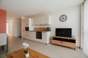 A modern kitchen with white cabinets, a built-in oven, and a wooden countertop. - Gites Les Ebihens - L'Arguenon (Saint-Cast-le-Guildo)