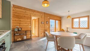 A modern kitchen with a dining area, wooden walls, and large windows. - Cosy Angelus, 4-person apartment 5 minutes from the slopes, mountain view terrace, parking. (Saint-Jean-de-Sixt)