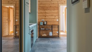 A modern kitchen with wooden paneling, a built-in oven, and a coffee maker on a shelf. - Cosy Angelus, 4-person apartment 5 minutes from the slopes, mountain view terrace, parking. (Saint-Jean-de-Sixt)