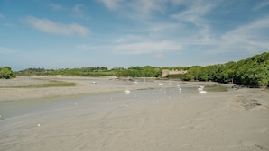 A wide riverbank with boats and a castle-like structure in the background. - Gites Les Ebihens - Pierres Sonnantes (Saint-Cast-le-Guildo)