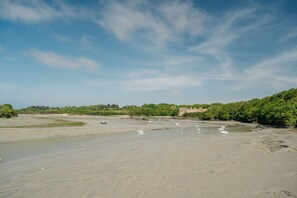 A wide riverbank with boats and a castle-like structure in the background. - Gites Les Ebihens - Pierres Sonnantes (Saint-Cast-le-Guildo)