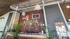 A reception area with a sign reading 'ARWANA RESORT,' a ceiling fan, and a decorative wall with flags. - Perhentian Arwana Resort - Telok Dalam (Pulau Perhentian Besar)