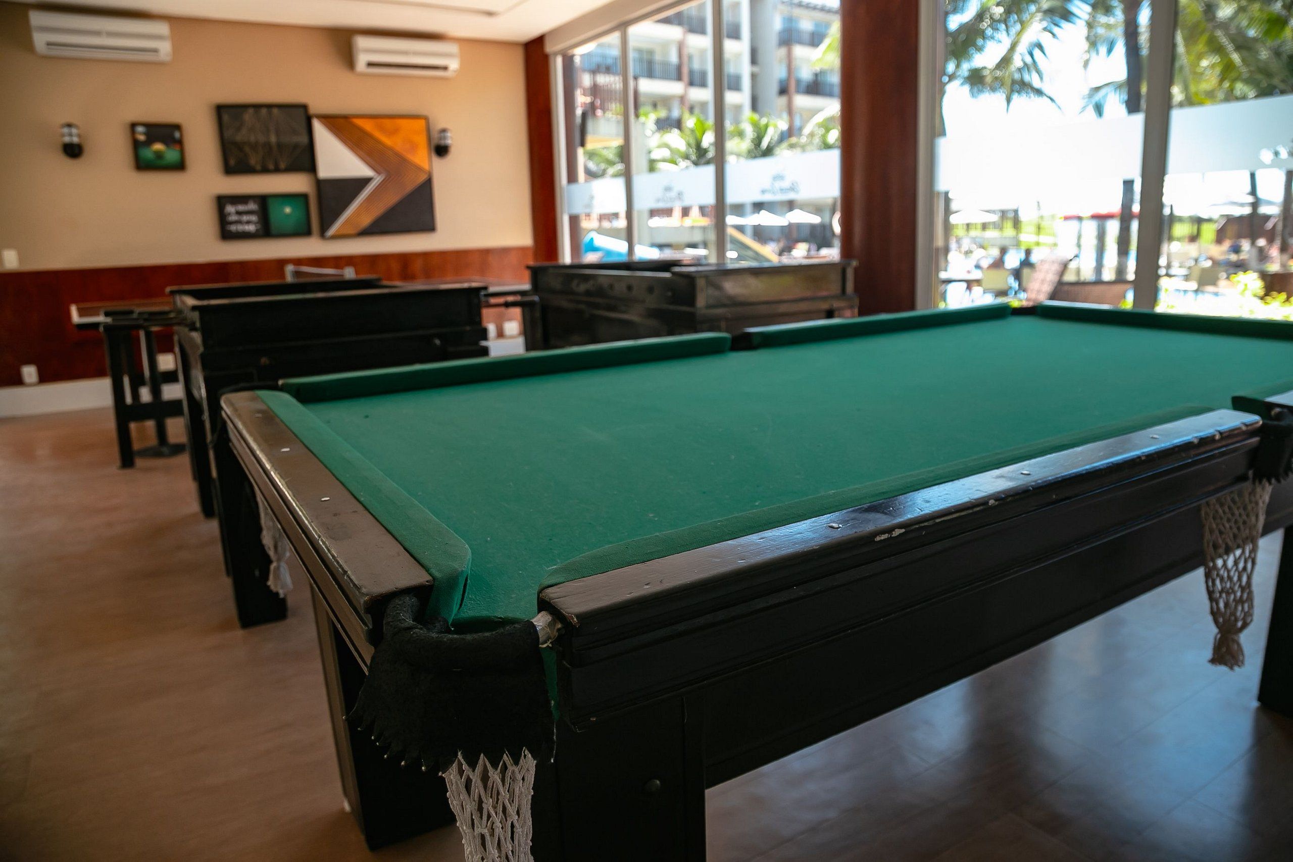 Una mesa de billar en una habitación con vista a palmeras.