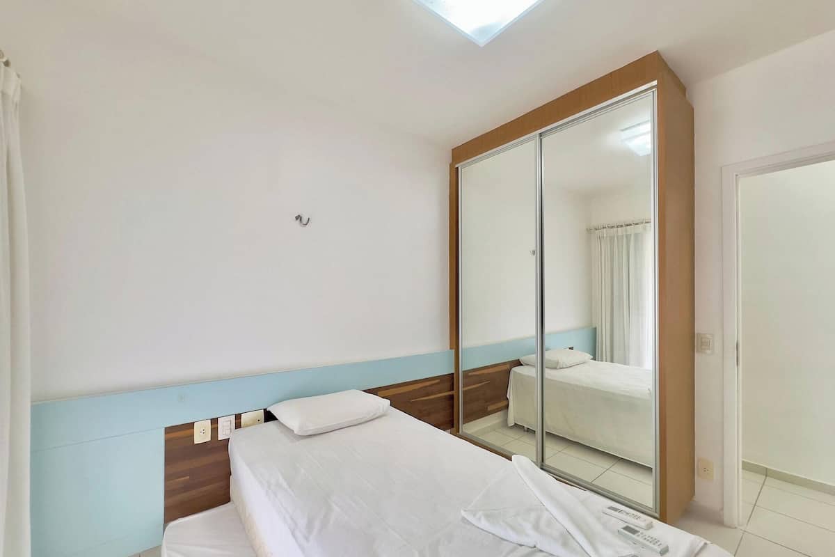 Habitación de hotel con cama, espejo, armario y tragaluz.