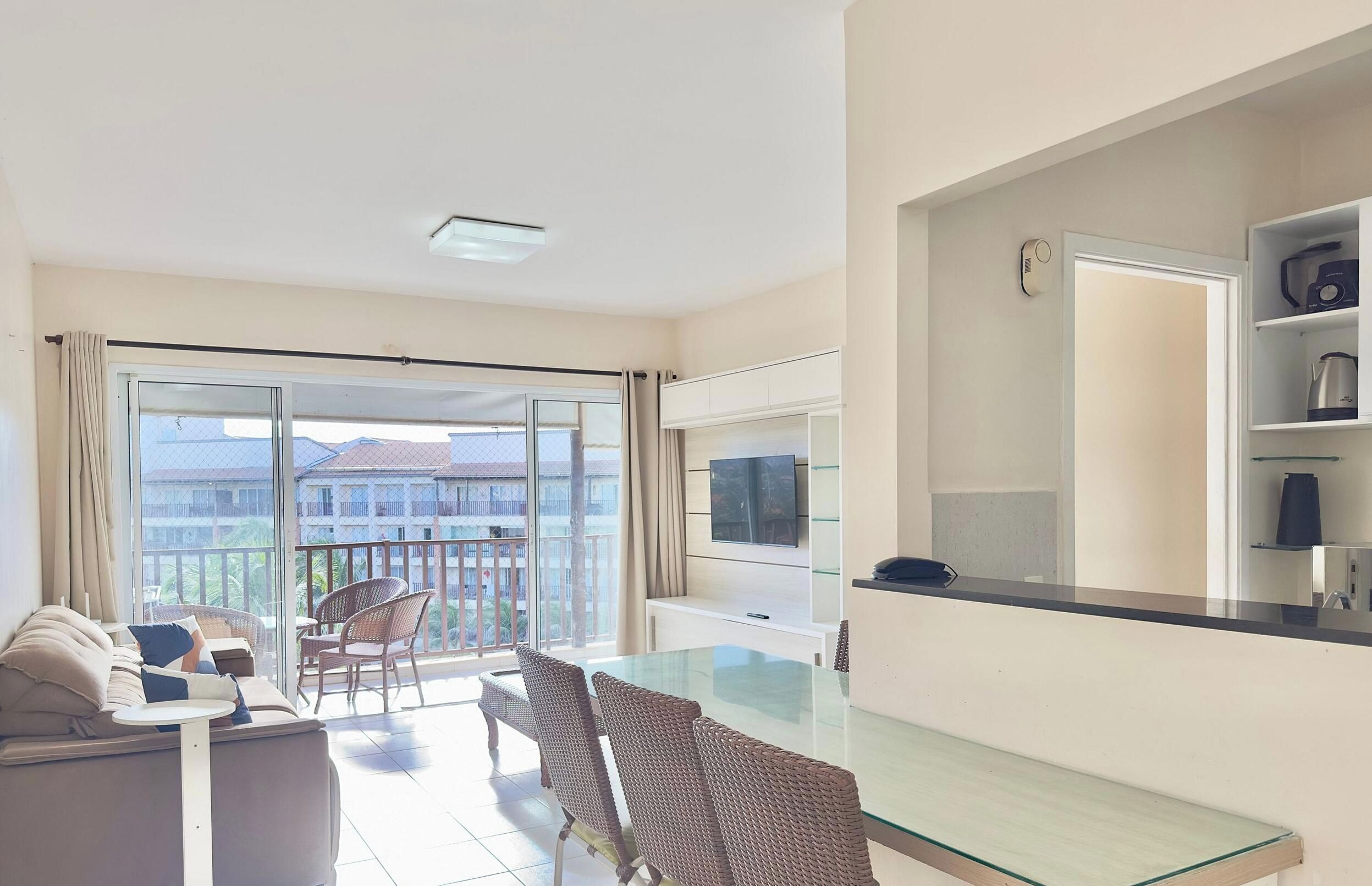 Uma sala de estar moderna com uma mesa de jantar de vidro, um sofá e uma televisão.