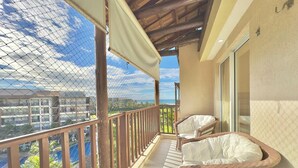 A balcony with wicker furniture, a view of a building complex, and a clear sky. - Beach Living Pe na Areia por Be My Guest (Aquiraz)