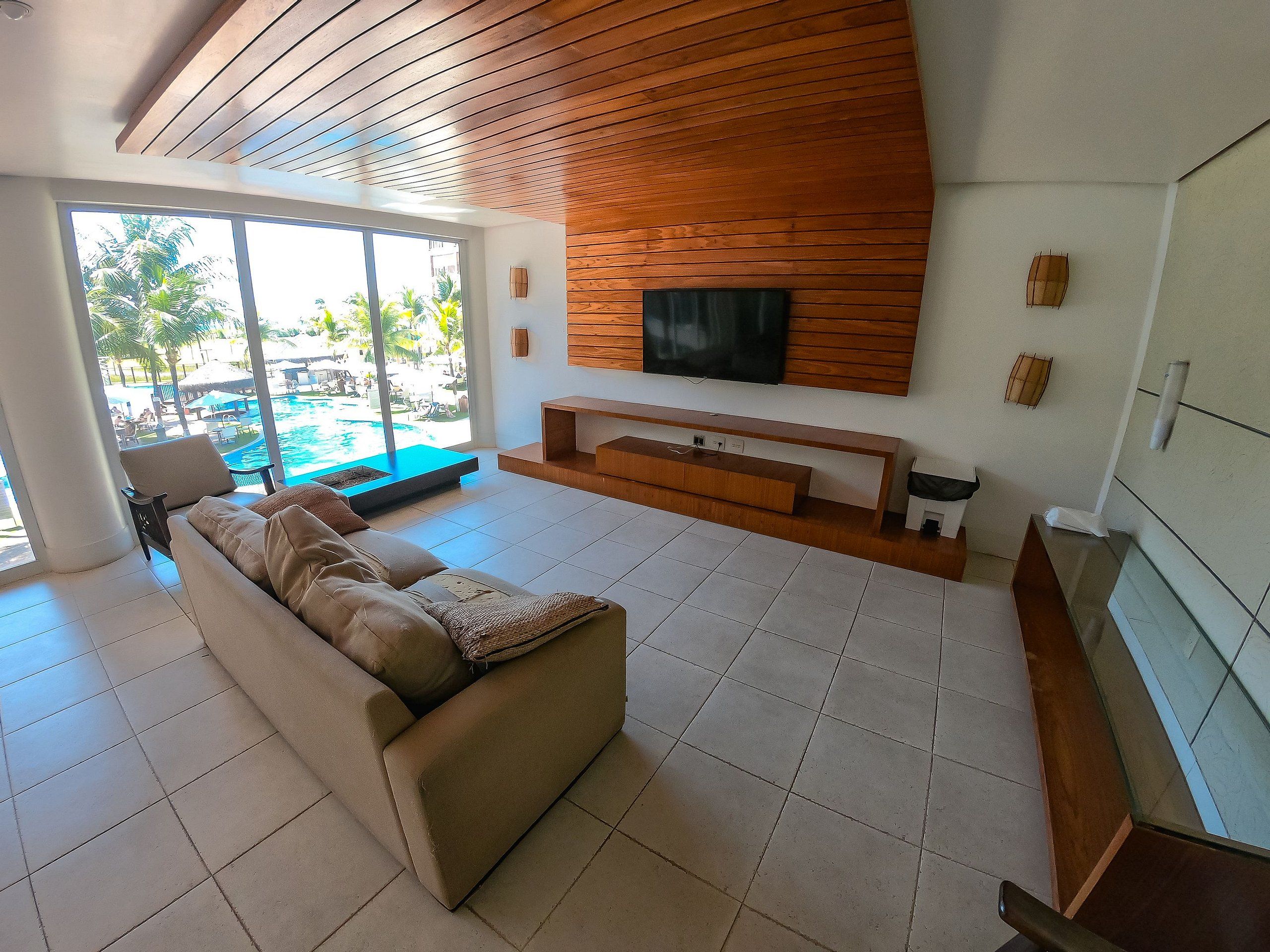 Una sala de estar moderna con un televisor grande, un sofá y vistas a una piscina exterior.