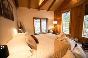 Une chambre dans une cabane en bois, avec un lit, des oreillers, une lampe et une fenêtre.