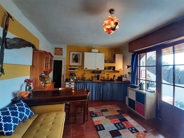A compact kitchen with a dining area, a patterned rug, and a window with curtains.