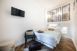 A bedroom with a bed, a chair, a television, and artwork on the wall. - Luxury apartment in the center of town (Nice)