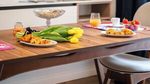 Ein Frühstückstisch mit Croissants, einem Glas Orangensaft und einer Schale Erdbeeren.