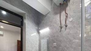 Un baño con lavamanos, espejo, papel higiénico y ducha.