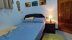 Un dormitorio con cama, mesita de noche, lámpara, una puerta y aire acondicionado instalado en la pared.