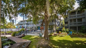 Un hotel a più piani con posti a sedere all'aperto, un molo e un giardino curato.