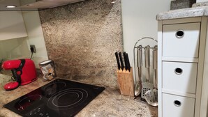 A kitchen with a black induction cooktop, a red toaster, a coffee maker, and a knife block. - La Concha Apartment (Donostia / San Sebastián)