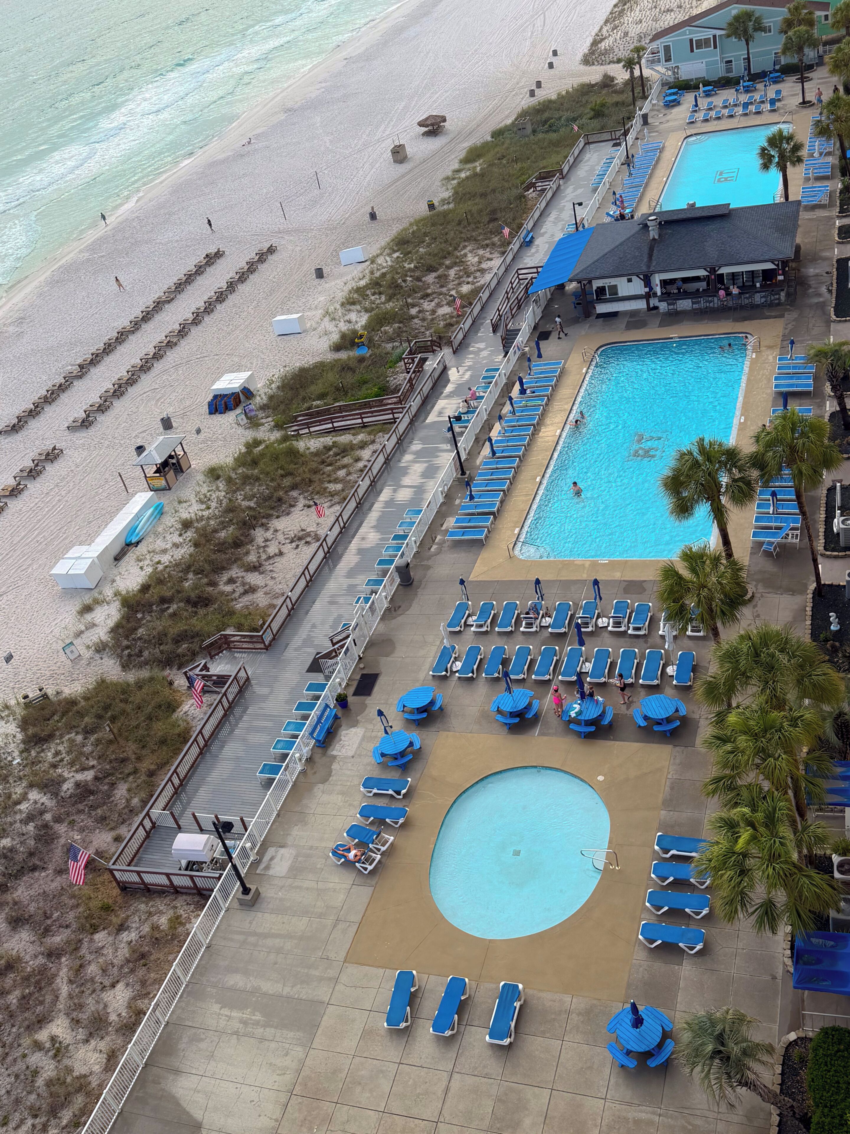 Un hôtel situé en bord de mer, doté d’une piscine, de chaises longues et d’une tour de surveillance pour les sauveteurs.