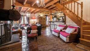 A spacious living area with a wooden staircase, a fireplace, and a dining area.