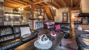 A cozy living room with leather sofas, a wooden coffee table, and a chandelier.