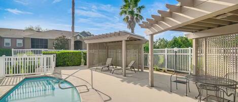 A residential backyard with a swimming pool, patio furniture, and a pergola.