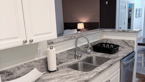 A kitchen with white cabinets, a granite countertop, a stainless steel sink, and a dishwasher. - BRAND NEW 3BR Coastal Retreat near OWA, shopping & min fr Gulf Shores beaches (Foley)