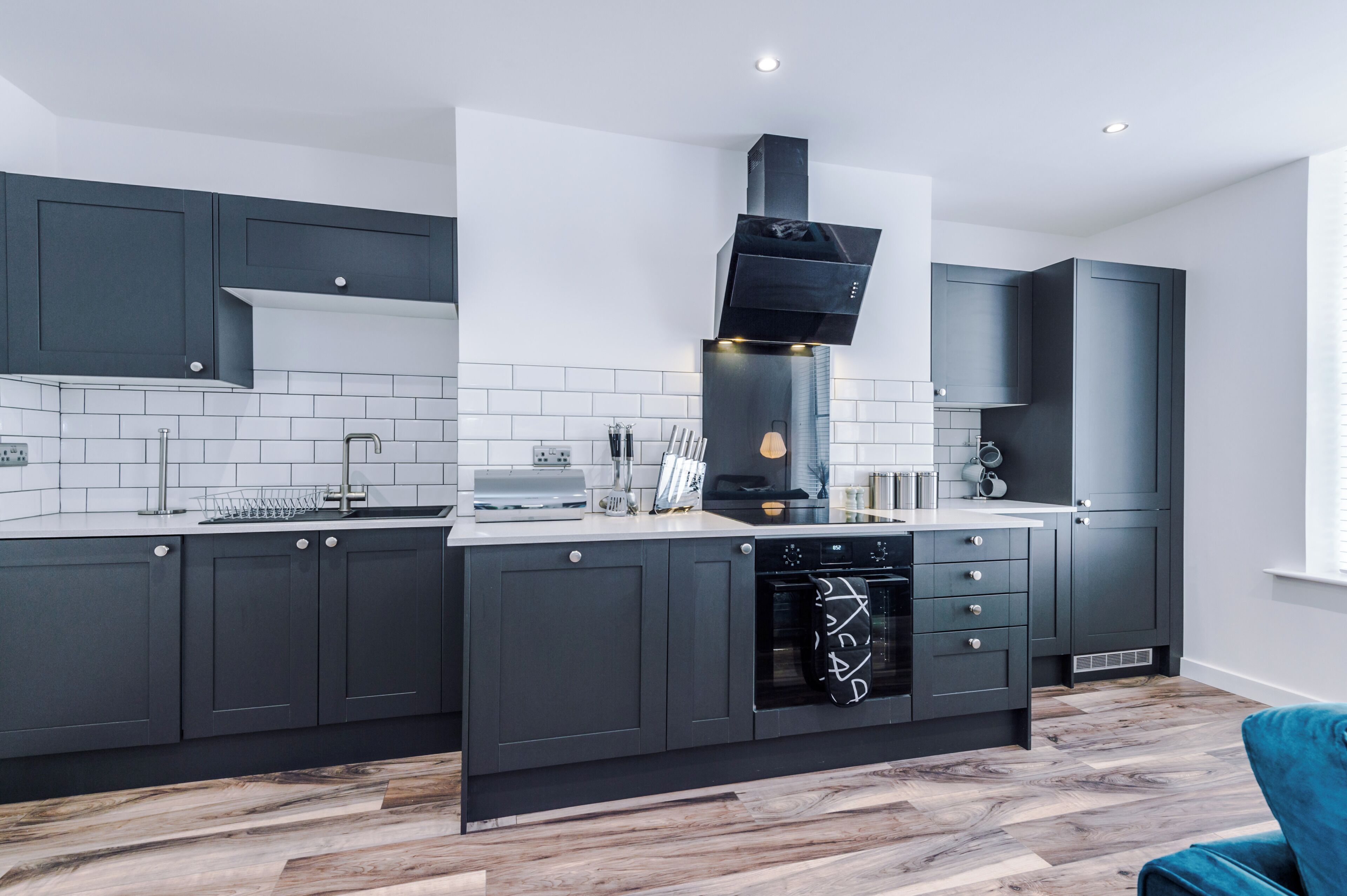 A modern kitchen with dark cabinets, a built-in oven, and a tiled backsplash.