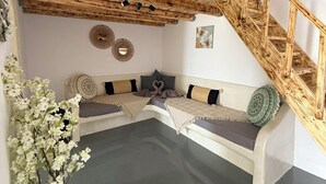 Een modern interieur met een houten trap, een zithoek met kussens en decoratieve muurkunst.
