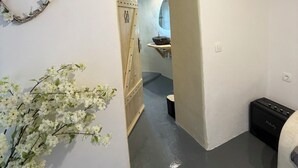 Een smalle gang met een houten plafond, een witte muur en een klein plantje.