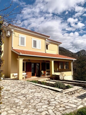 A two-story building with a tiled roof, a covered porch, and a stone-paved courtyard. - Villa Provence Budva (Budva)