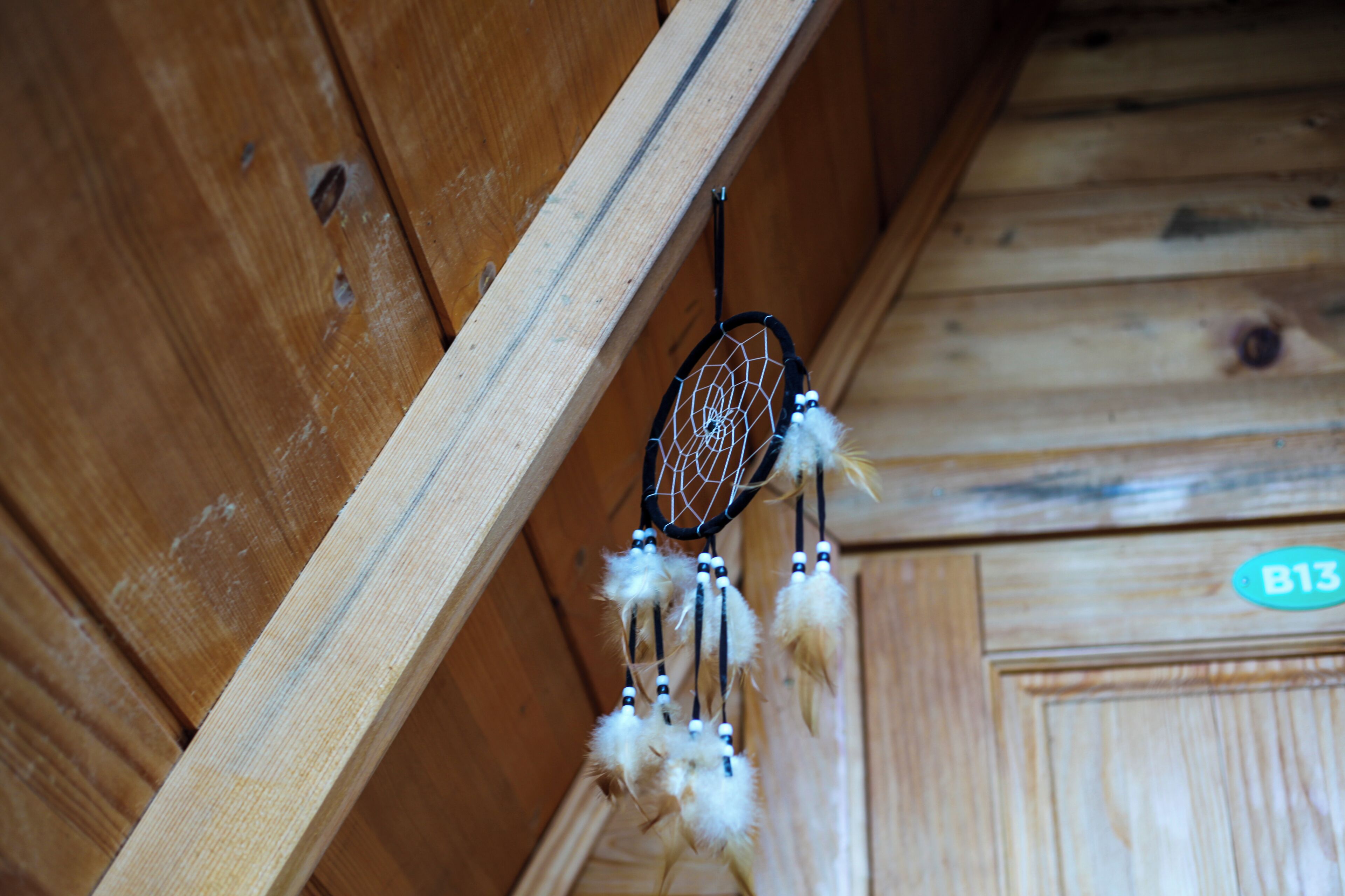 A wooden interior with a dreamcatcher hanging from a beam.