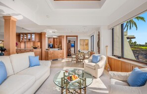 A spacious living area with a sofa, armchairs, a glass coffee table, and a view of the outdoors.
