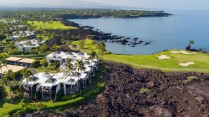 Un complejo turístico con varias edificaciones tipo bungalow, un campo de golf y vista al océano.