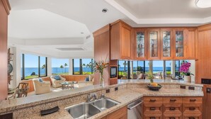 Una cocina moderna con encimeras de granito, armarios de madera y vistas al océano.