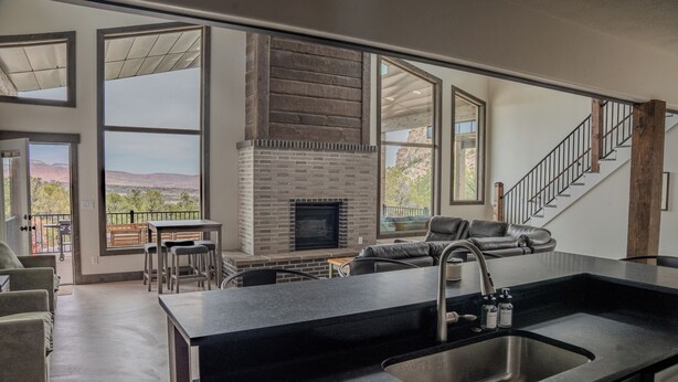 A modern kitchen with a large island, a fireplace, and a view of mountains.