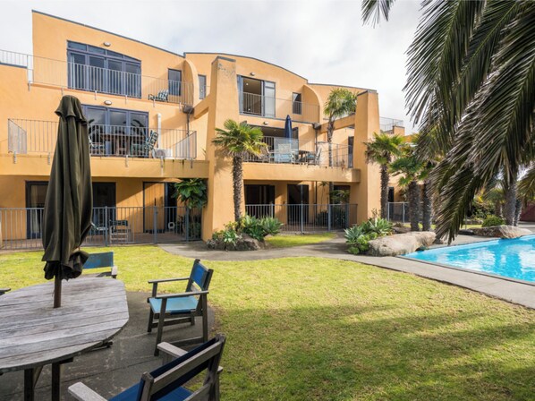 Un immeuble de deux étages doté de balcons, d’une piscine et d’un espace extérieur am énagé pour s’asseoir.
