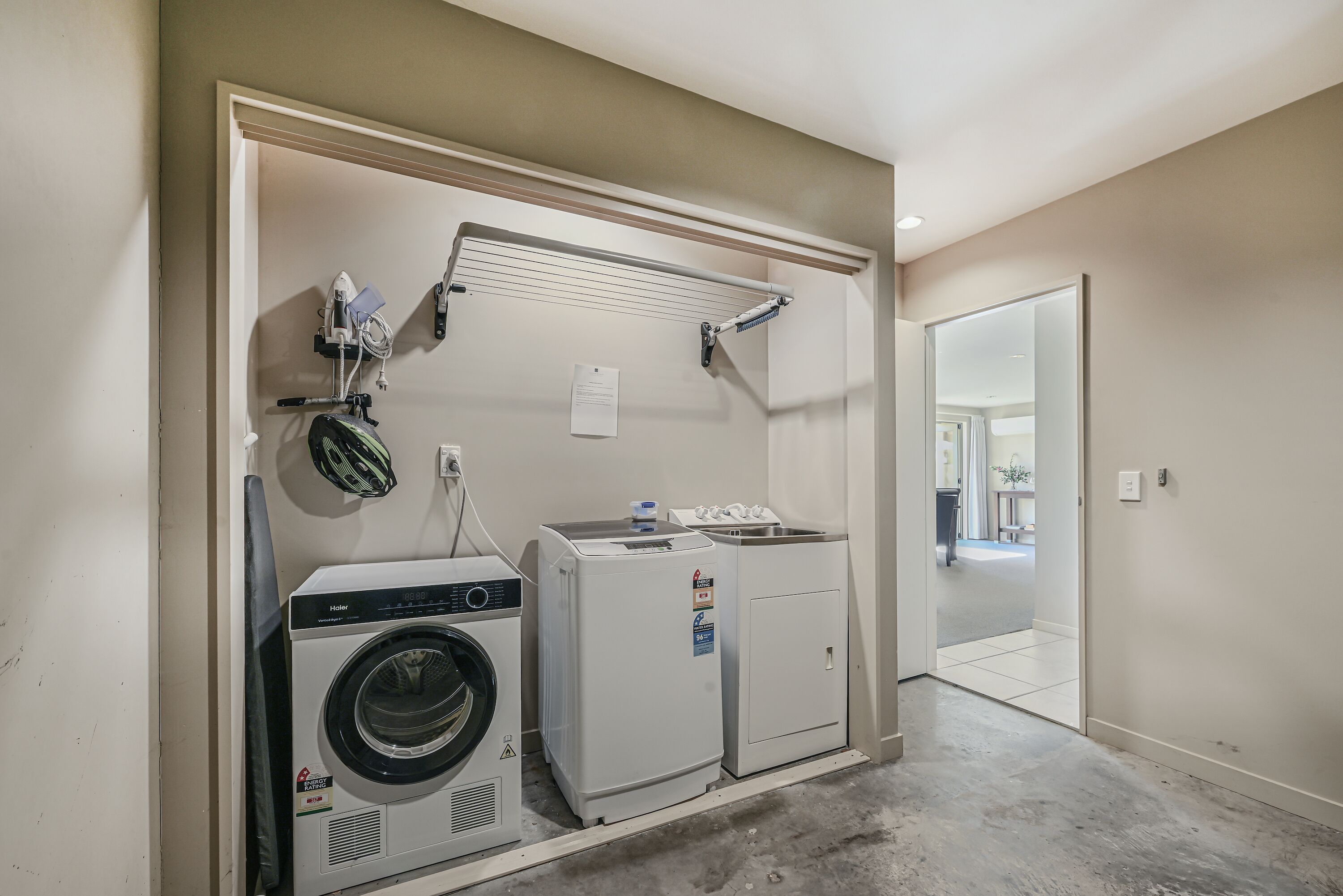 A laundry room with a washer, dryer, and drying rack.