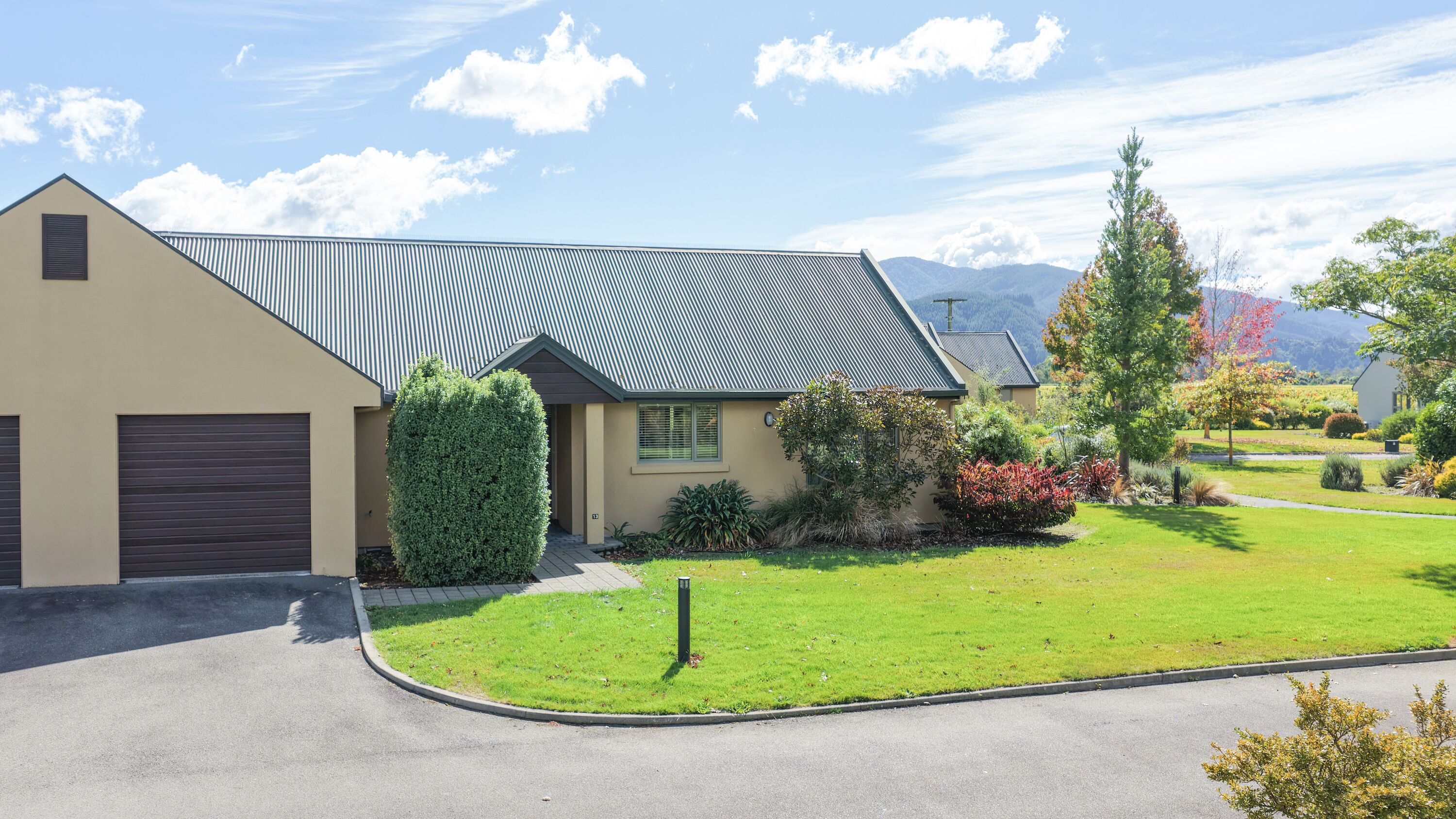 A residential house with a sloped roof, a garage, and a well-maintained lawn.