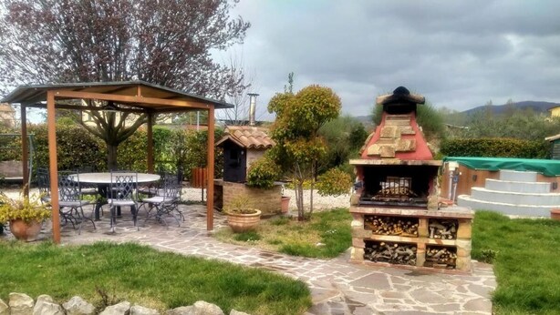 An outdoor patio area with a grill, a covered seating area, and a stone pathway. - Villa a stone's throw from Assisi with pool and barbecue, for a relaxing stay (Tordibetto)