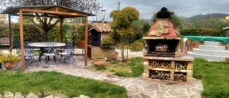 An outdoor patio area with a grill, a covered seating area, and a stone pathway.