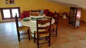 A dining area with a round table, chairs, a basket of bread, and a vase with flowers. - Villa a stone's throw from Assisi with pool and barbecue, for a relaxing stay (Tordibetto)
