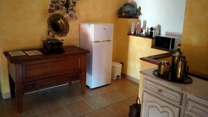 A kitchen with a refrigerator, wooden table, and cabinets. - Villa a stone's throw from Assisi with pool and barbecue, for a relaxing stay (Tordibetto)