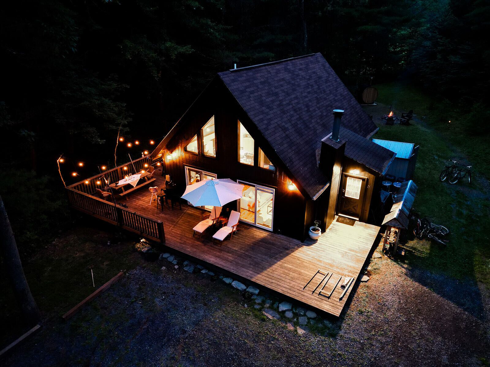 Une cabane en bois dotée d’une terrasse, de meubles d’extérieur et d’un grand parasol.