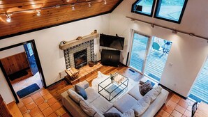 Een woonkamer in loftstijl met een open haard, een grote bank en een eethoek.