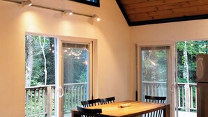 Een gezellig interieur met een houten plafond, een eettafel met stoelen en een bank met kussens.